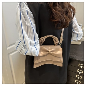 Détail du nœud décoratif et de la poignée torsadée sur le petit sac en cuir mat élégant