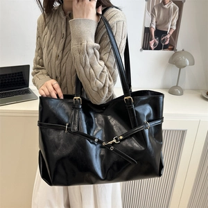 Large black minimalist tote bag in glossy leather shown in a professional office setting