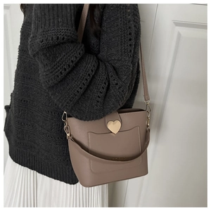 Détail du sac seau taupe avec grande boucle cœur dorée sur cuir grainé texturé