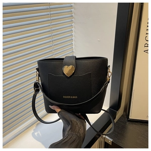 Détail du sac seau noir avec texture litchi et boucle dorée en forme de cœur