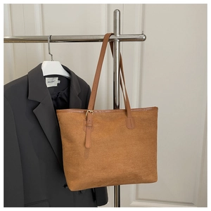 Detail view of brown faux suede tote bag with adjustable shoulder strap and metal buckle