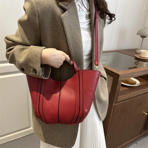Red leather bucket bag with stitching details and adjustable shoulder strap shown on model