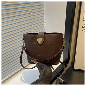 Détail d'un sac seau marron avec fermoir coeur doré et texture de cuir grainé litchi