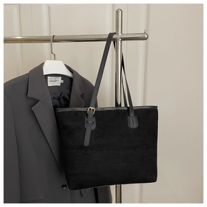 Detail of black matte tote bag with slim shoulder strap and golden metal buckle detail