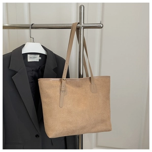 Detail of camel suede tote bag with leather straps and adjustable metal buckle