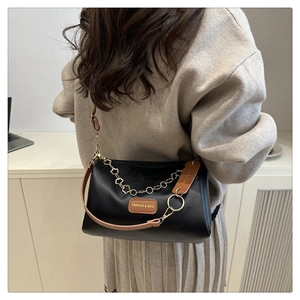Detail view of black leather pillow bag with gold floral chain and embossed leather label
