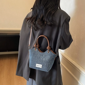 Borsa a tracolla in denim retrò con finiture in pelle e manico annodato su una modella