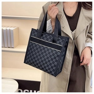 Detail of black tote bag featuring textured star pattern and wide fabric handles