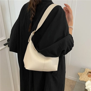 Minimalist cream white leather hobo bag with wide shoulder strap shown in a fashion styling