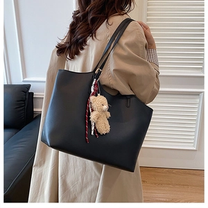 Close-up of black tote bag featuring matte texture and a cute plush bear charm detail