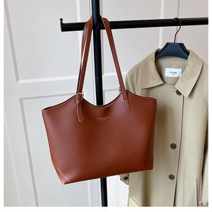 Detail of a brown leather tote bag with gold FASHION & BAGS lettering on minimalist hanger