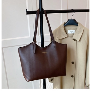 Close-up of dark brown leather tote bag with gold lettering and adjustable straps