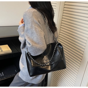 Detail der glänzenden schwarzen Lackleder-Schultertasche mit Knitteroptik und Kette