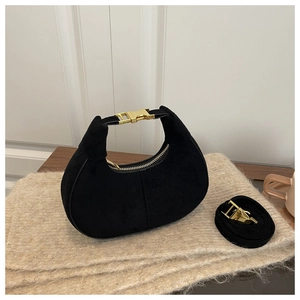 Gros plan du sac hobo en daim noir avec boucle dorée sur une surface en tricot