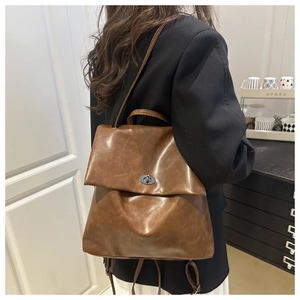 Detail of vintage brown leather backpack with metal twist lock worn with a black blazer