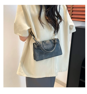 Detail of a dark gray gradient crossbody bag with a unique knot handle on a model