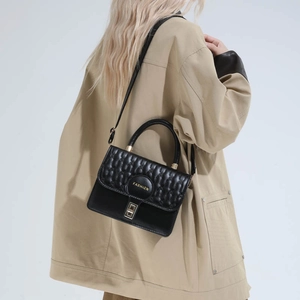 Chic black quilted crossbody handbag with gold buckle and adjustable strap shown on model