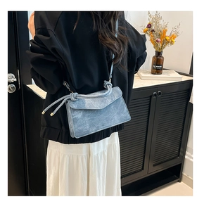 Detail of light blue crossbody bag with knot handle decoration and adjustable strap