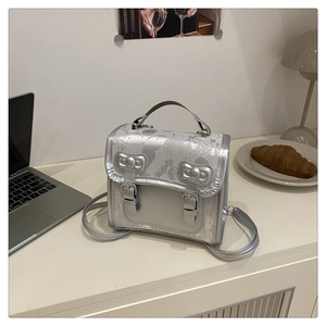 Détail d'un sac à dos argenté avec nœud papillon et texture d'encre sur le bureau