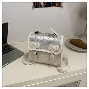Détail du sac à dos nœud papillon crème avec motifs papillons argentés sur bureau