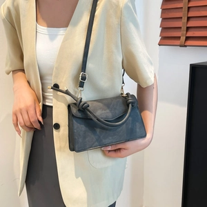 Charcoal grey matte crossbody bag with unique knot handle and gold hardware on model