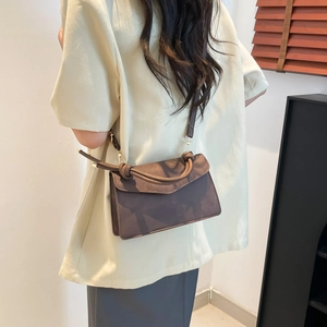 Brown gradient crossbody bag with unique knot handle and gold hardware in lifestyle setting