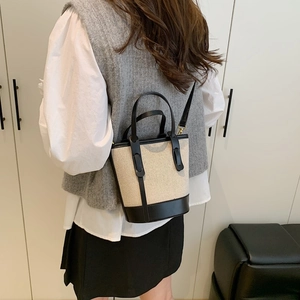 Minimalist canvas and leather contrast bucket bag with detachable shoulder strap shown on model