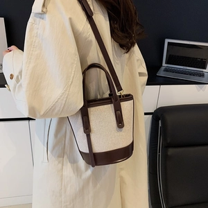 Chic canvas and coffee leather bucket bag shown in a professional lifestyle office setting