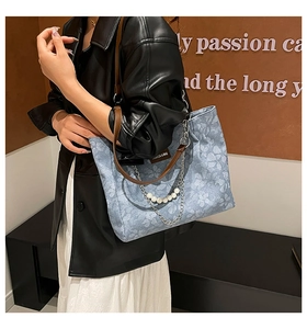 Detail of floral denim tote bag featuring luxury pearl chain and leather shoulder strap
