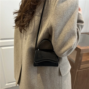 Petit sac carré noir minimaliste avec rabat ondulé et poignée en cuir élégante