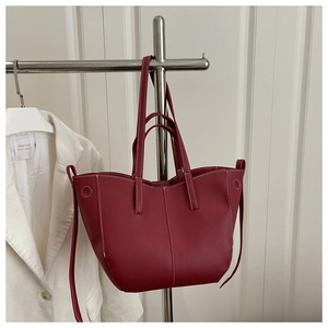 Detail of dark red leather tote bag showing white contrast stitching and pebble texture