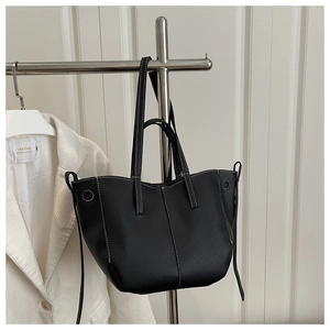 Detail of black lychee grain leather tote bag with white contrast stitching on hanger