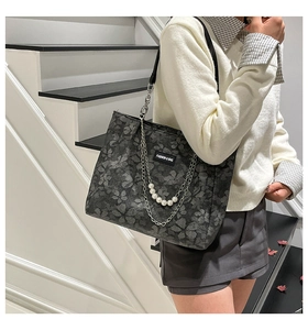 Detail of dark grey tote with floral print, leather straps, and white pearl chain decoration