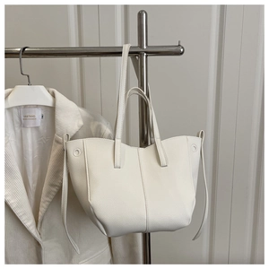 Detailed macro view of white pebble textured leather tote bag on a metal hanger display