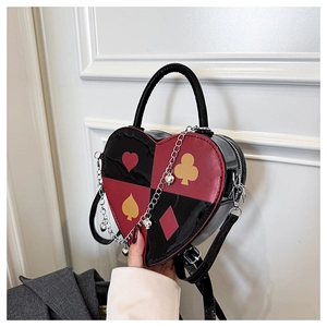 Macro shot of heart-shaped crossbody bag featuring poker card motifs and red-black leather