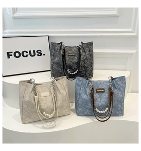 Detailed shot of textured floral tote bags with silver chains and pearl decorations