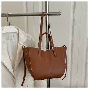 Macro shot of brown pebble leather tote bag with white stitching and drawstring details