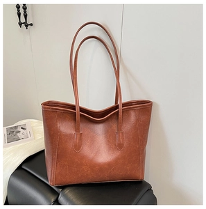 Grande borsa shopper marrone vintage in ecopelle su una sedia nera di classe
