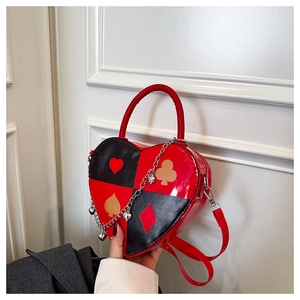 Macro detail of heart-shaped crossbody bag with poker motifs and metallic charms
