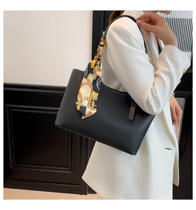 Detail of black leather tote bag with white stitching and printed silk scarf accessory