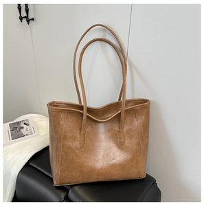 Dettaglio della borsa tote vintage marrone con trama in pelle su una panca nera