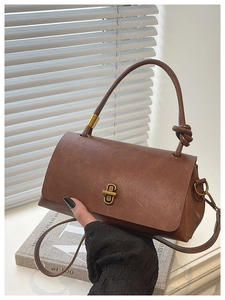 Detail of vintage brown leather bag with thick knot handle and matte gold hardware buckle
