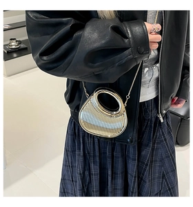 Mini sac argenté à textures verticales porté par un mannequin dans un studio moderne
