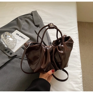 Détail du sac nuage marron foncé brillant avec fermoir magnétique et texture cuir plissé