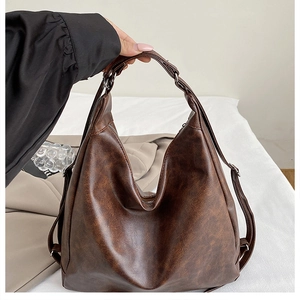 Detail of deep brown textured faux leather hobo bag with zipper and metal buckle