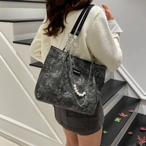 Deep grey jacquard tote bag with pearl chain strap and minimalist logo on model