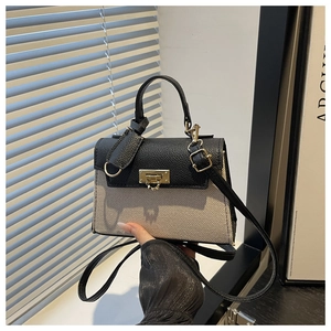 Detail of a mini two-tone handbag featuring black textured leather and beige canvas textures