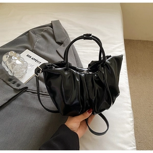 Détail d'un sac nuage plissé noir brillant avec poignée et fine bandoulière amovible