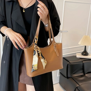 Brown matte leather tote bag with printed silk scarf shown on model in modern room