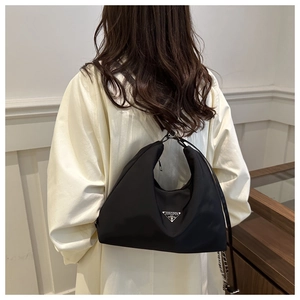 Detail of black nylon hobo bag with silver chain strap and triangular metal plaque